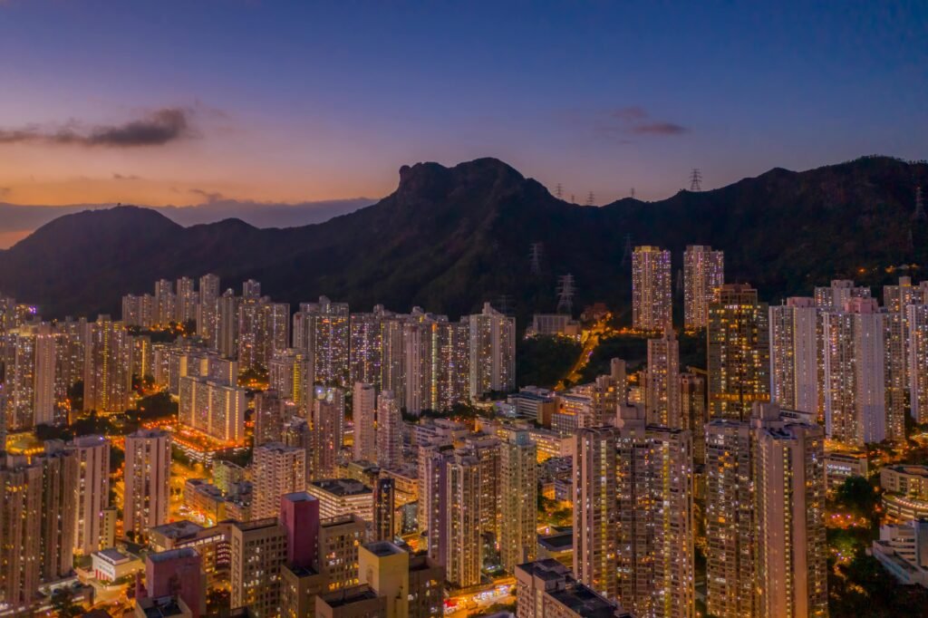 Stunning aerial shot of Kowloon, Hong Kong at dusk with skyscrapers and Lion Rock in the background.
